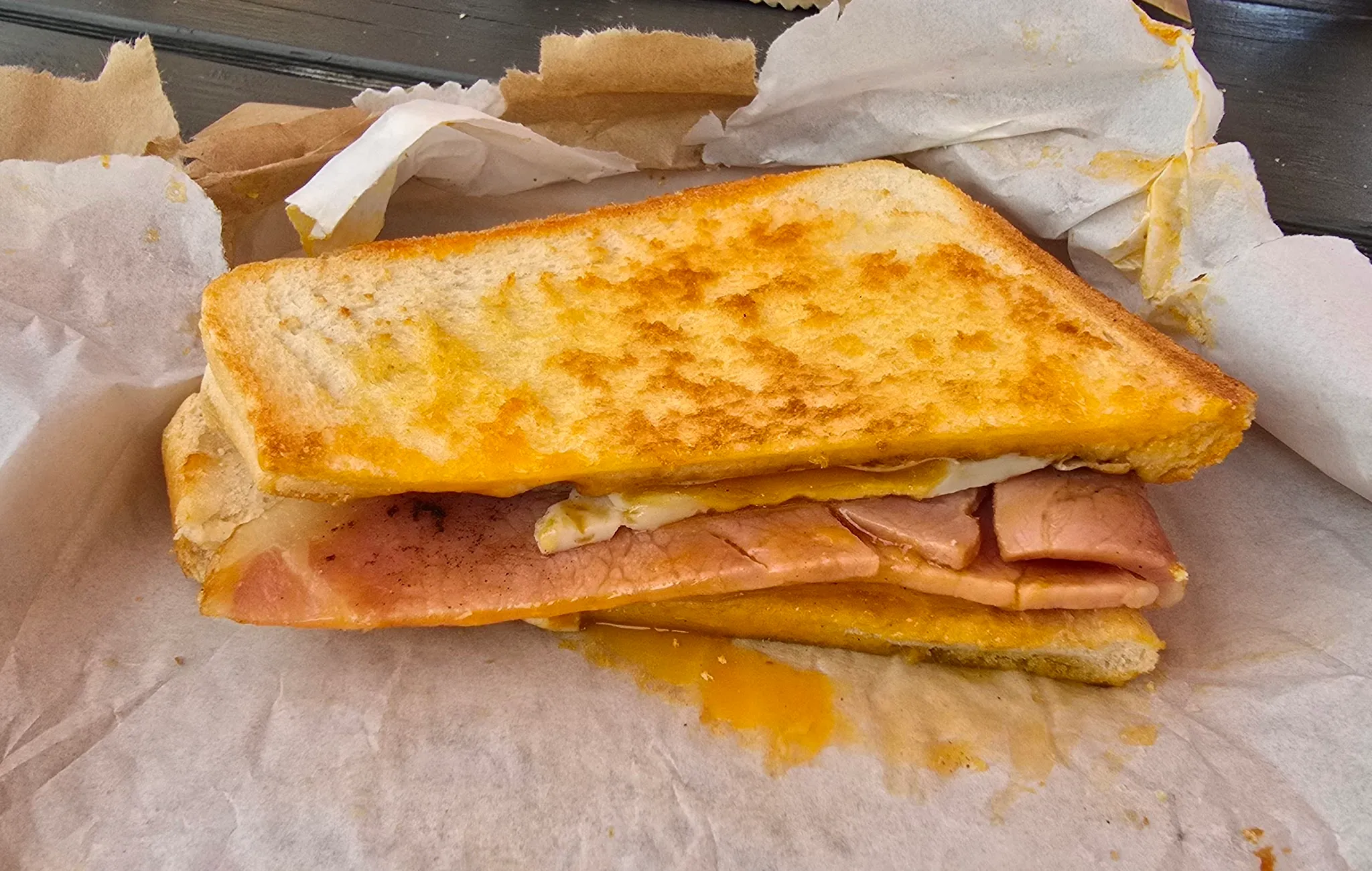 Toasted ham and cheese sandwich, fresh-pressed on a wooden board